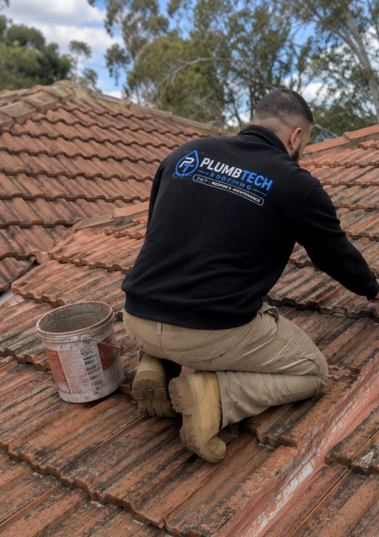 Plumbtech roofer re-bedding ridge capping on a terracotta tile roof